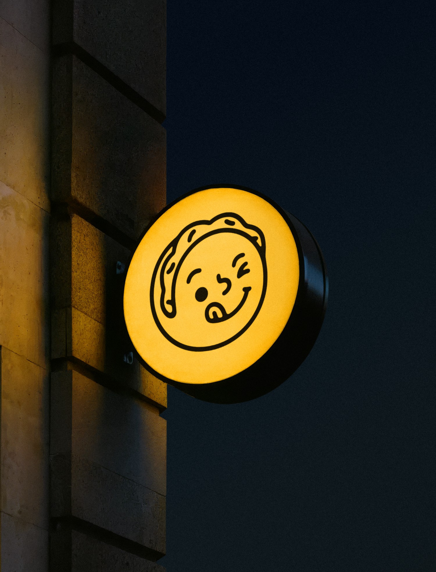 Illuminated blade sign with the mascot, at night
