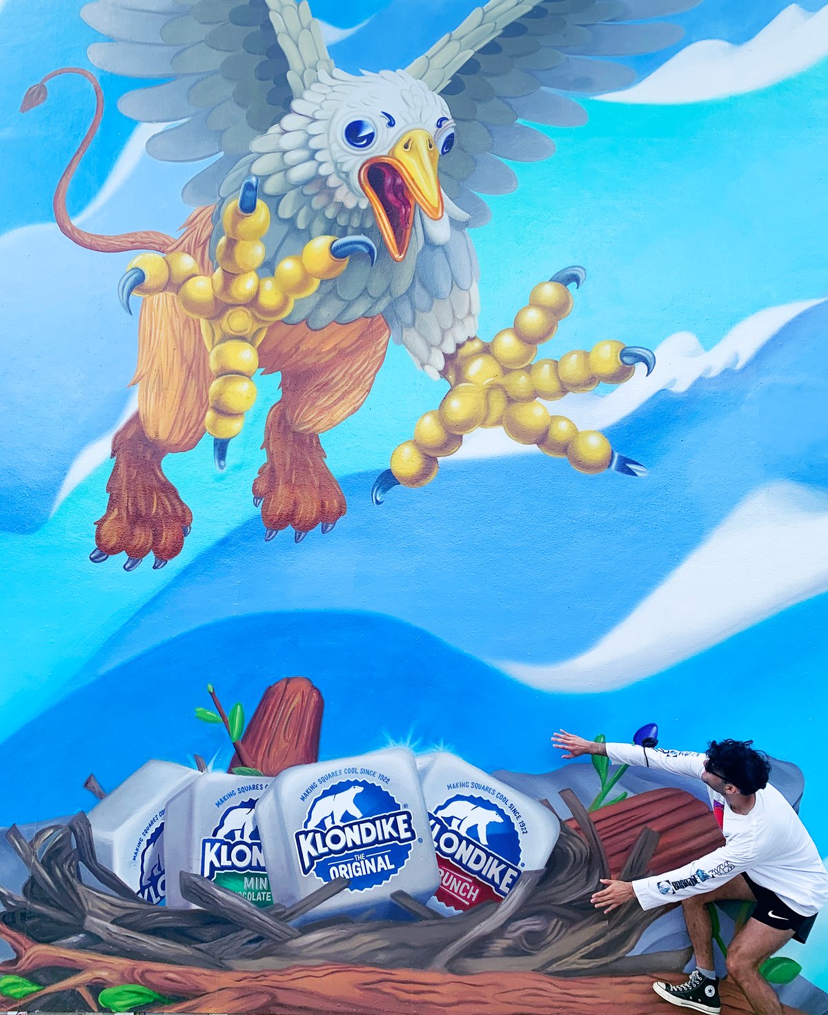 A visitor crouched under the griffin, reaching for the nest of Klondike bars