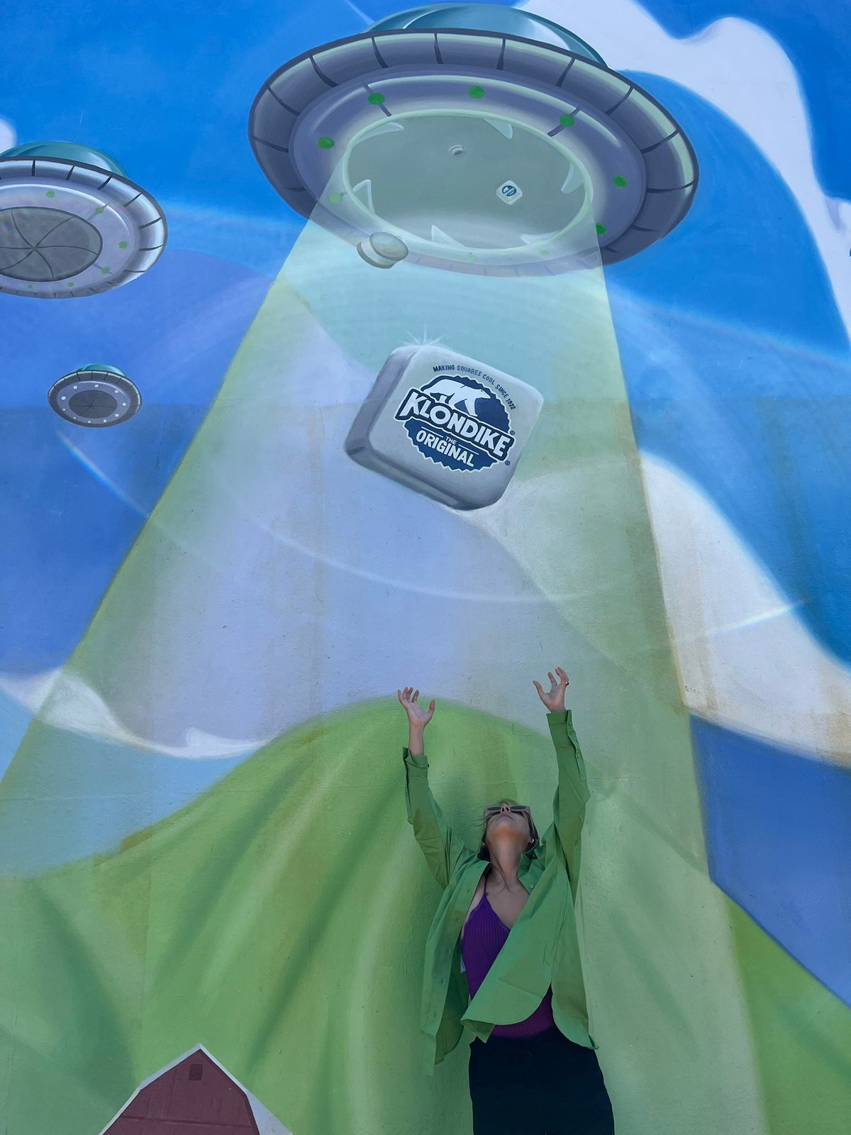 A visitor reaching up into the UFO&rsquo;s tractor beam toward a Klondike bar