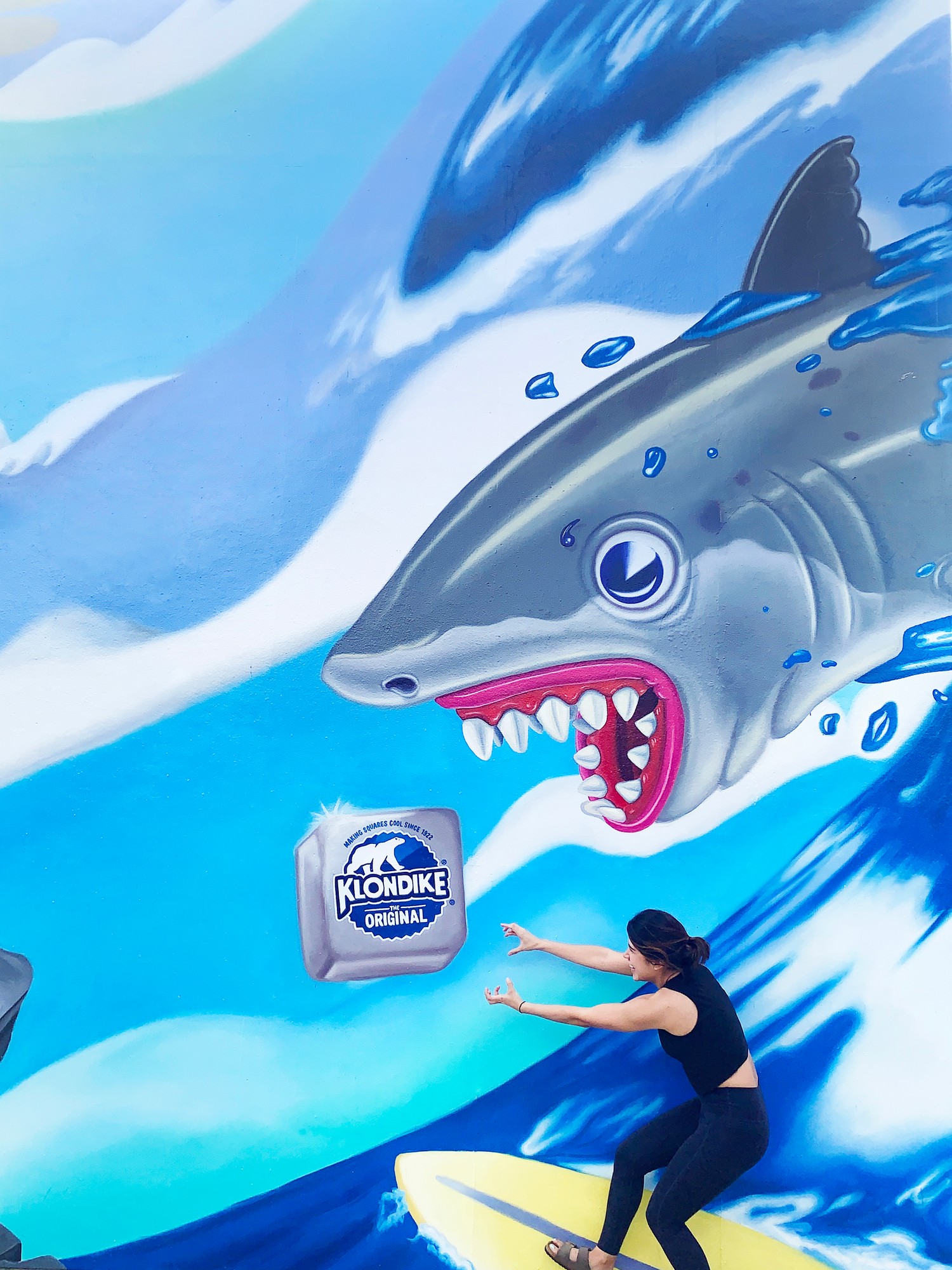 A woman on the painted surfboard, posing in front of the shark section