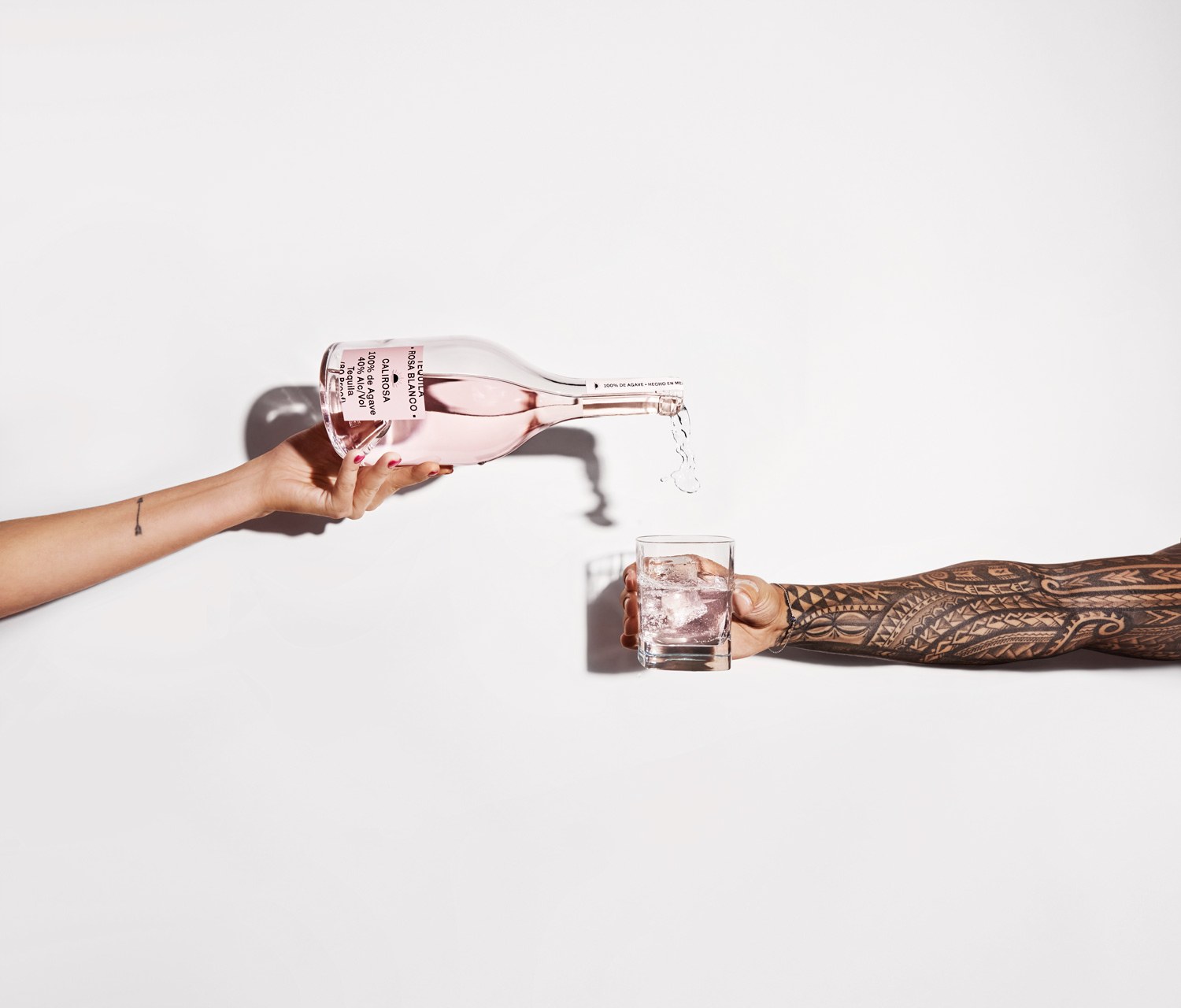 Two hands pouring Rosa Blanco tequila into a glass